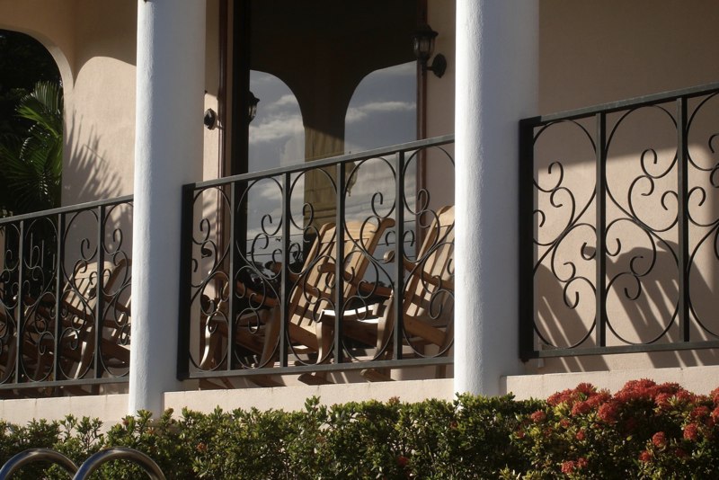 Four rocking chairs on front porch overlook the pool.