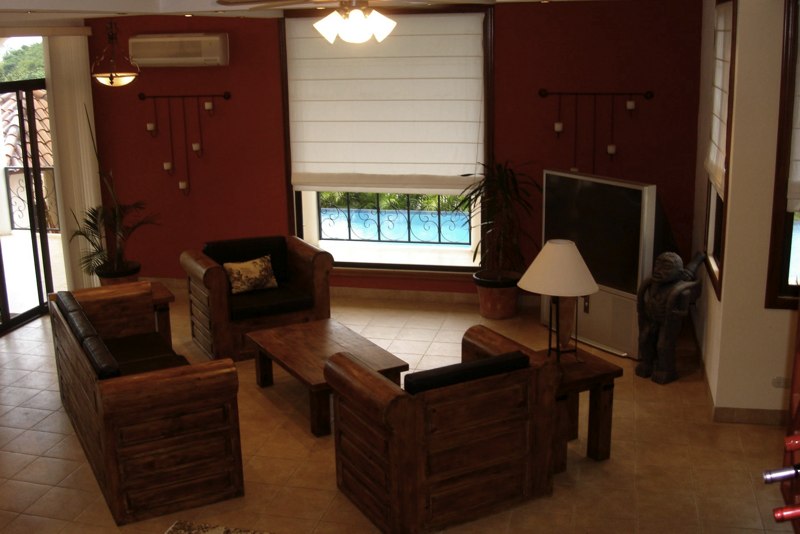 Fully furnished living room with large flat-screen TV and locally made leather sofa chairs and tables.
