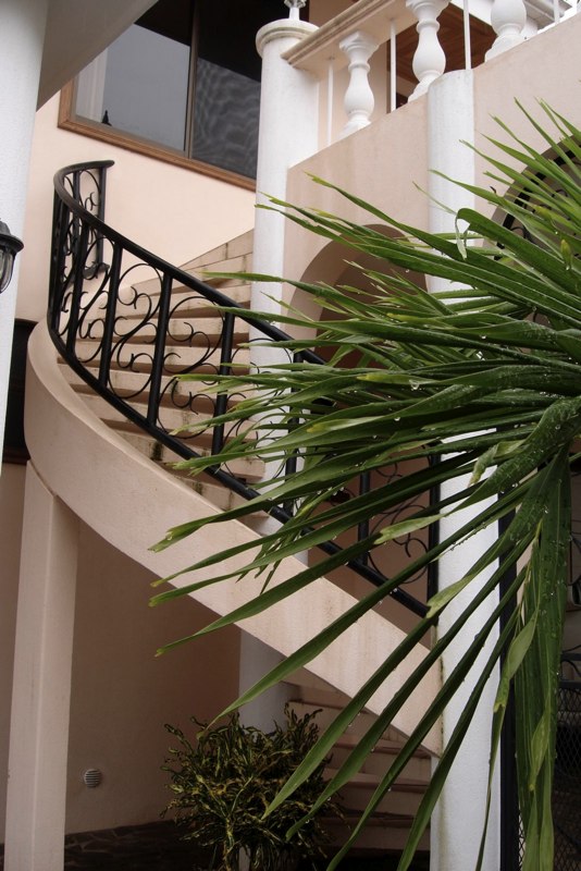 Staircase leading to a large secondary balcony with table and chairs.