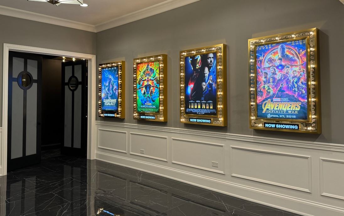 Home theater entrance with illuminated movie-poster marquees displayed along the wall