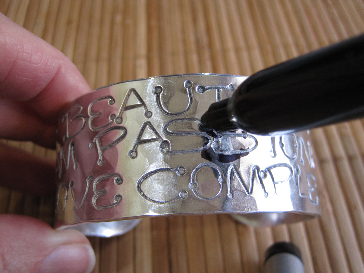 Using a black Sharpie to darken faded letters on a hand stamped cuff bracelet