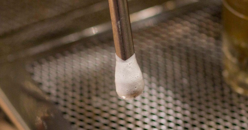 A steam wand with milk foam on it after frothing