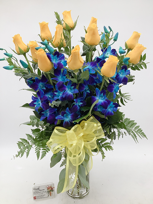 Blue orchids and yellow roses flower arrangement in glass vase